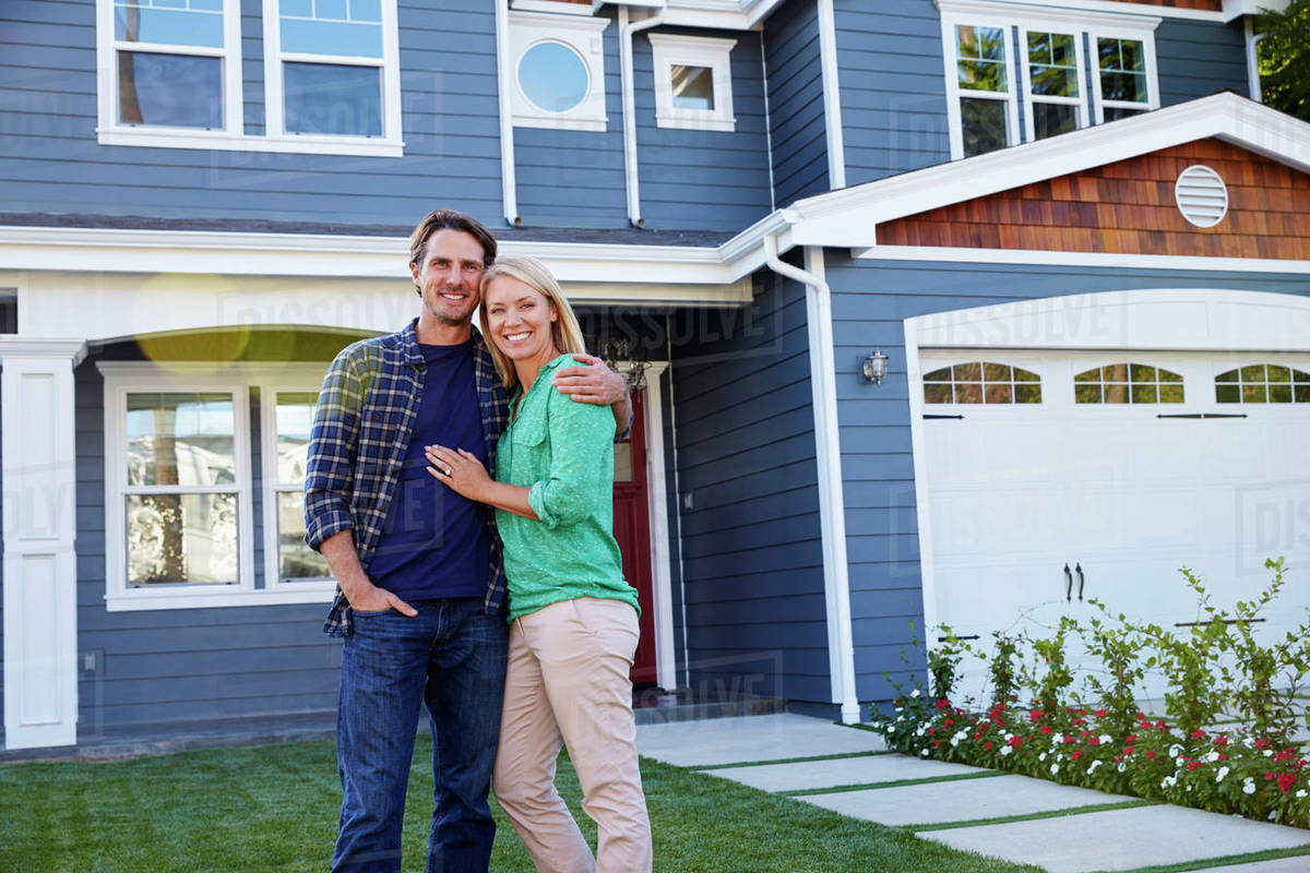 Portrait Of Couple Standing Outside House - Stock Photo - Dissolve