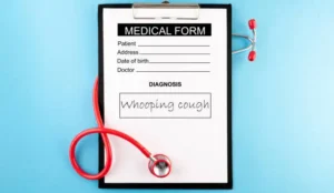 Clipboard with a medical form labeled 'Medical Form' showing the handwritten diagnosis 'Whooping cough,' and a red stethoscope coiled around it on a blue background.